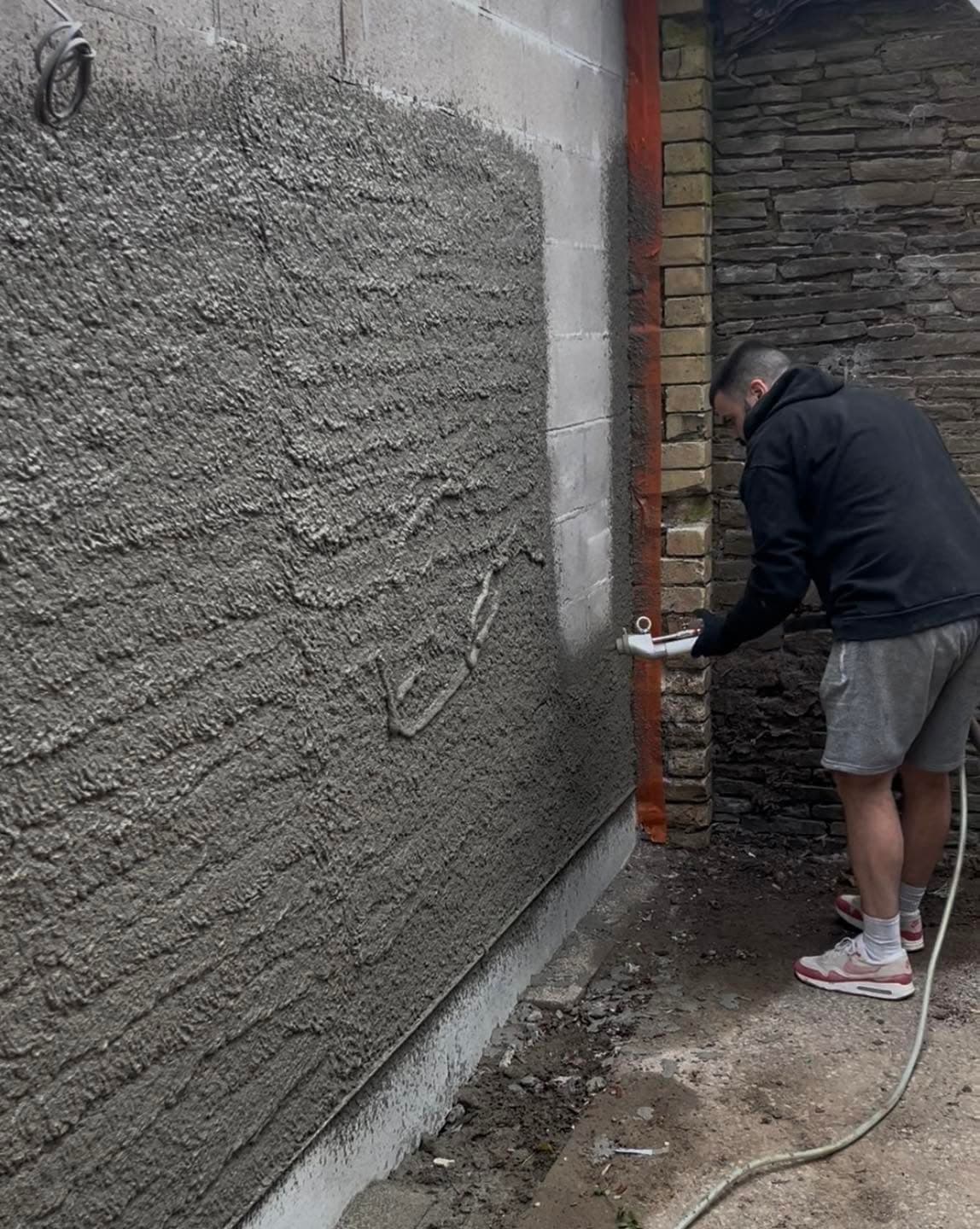 A DSL Plastering renderer applying a scratch coat of sand and cement render to a blockwork wall